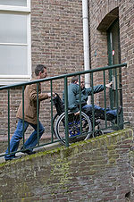 Een persoon in een rolstoel wordt een helling opgeduwd